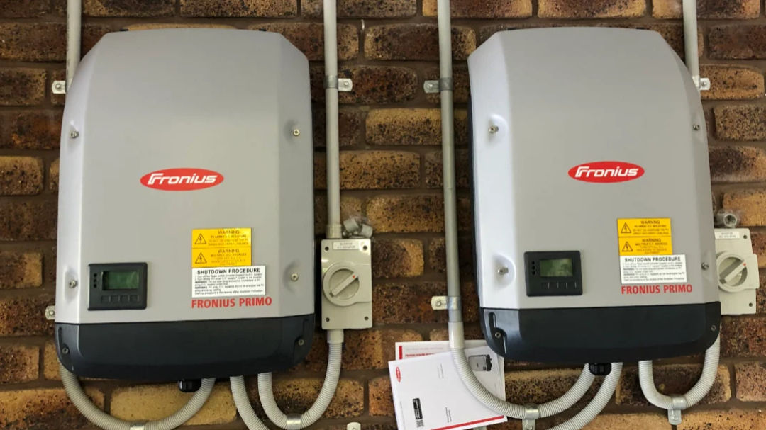 Image of two string inverters mounted on a brick wall.